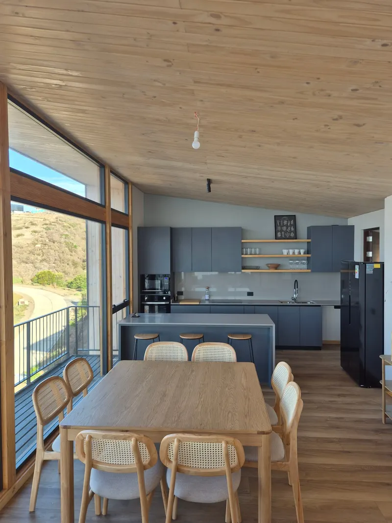 Comedor integrado con la cocina y ventanales hacia la terraza