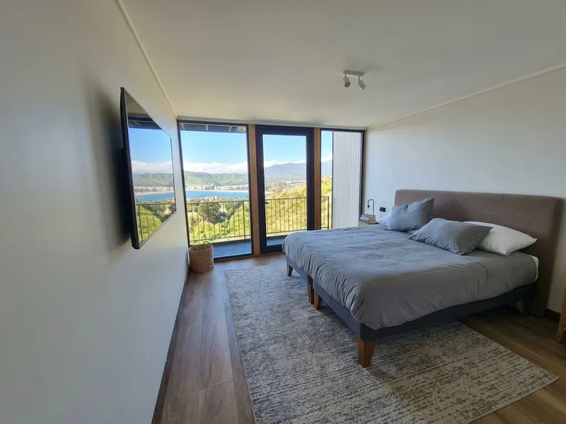 Dormitorio con cama de dos plazas y ventanales hacia la bahía de Papudo
